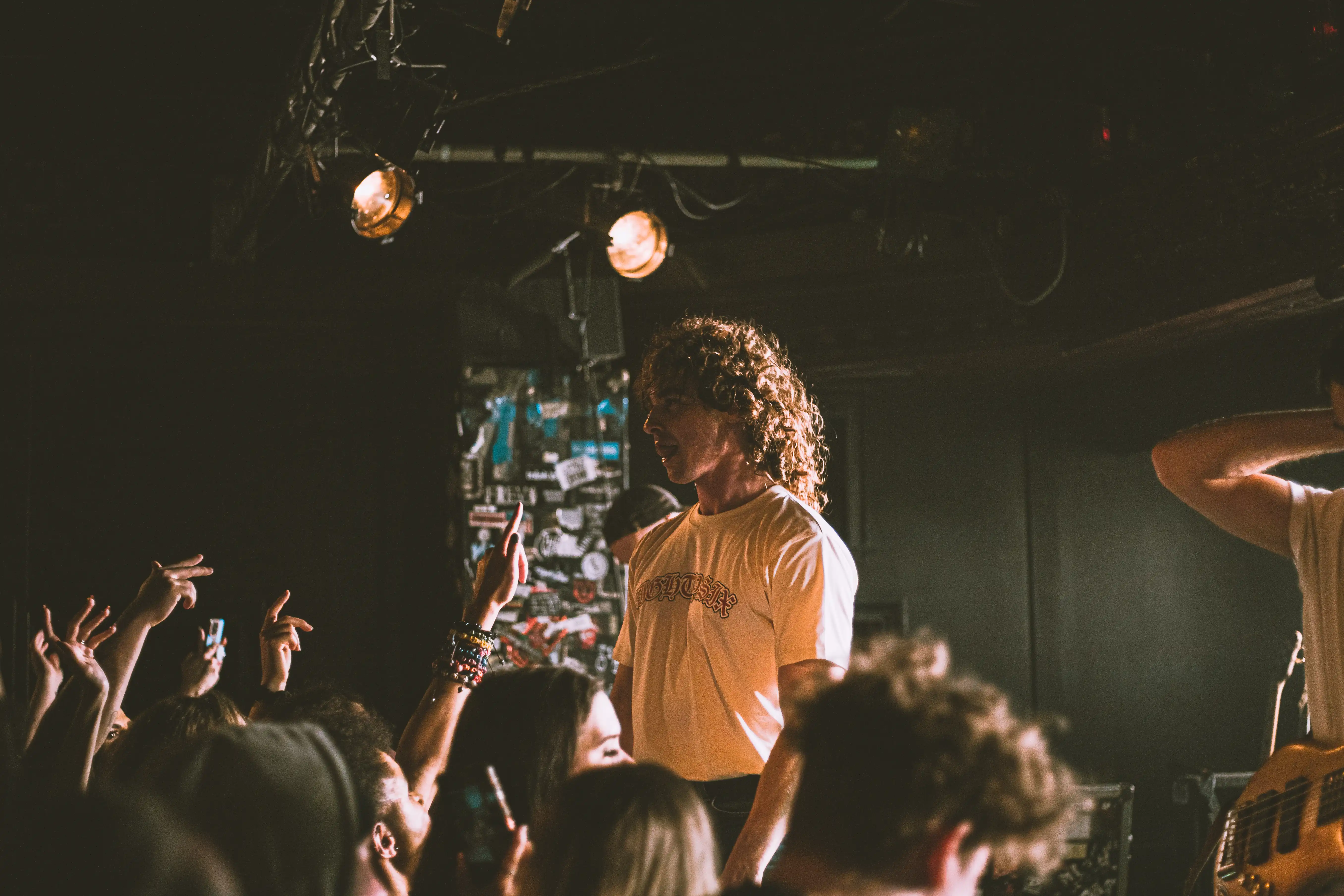 Front man of Don Broco, standing at the edge of the stage looking into a crowded audience.